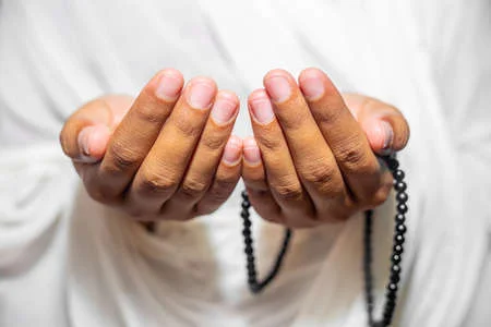 150595260 muslim women raise their hands to pray with a tasbeeh on white background indoors focus on hands